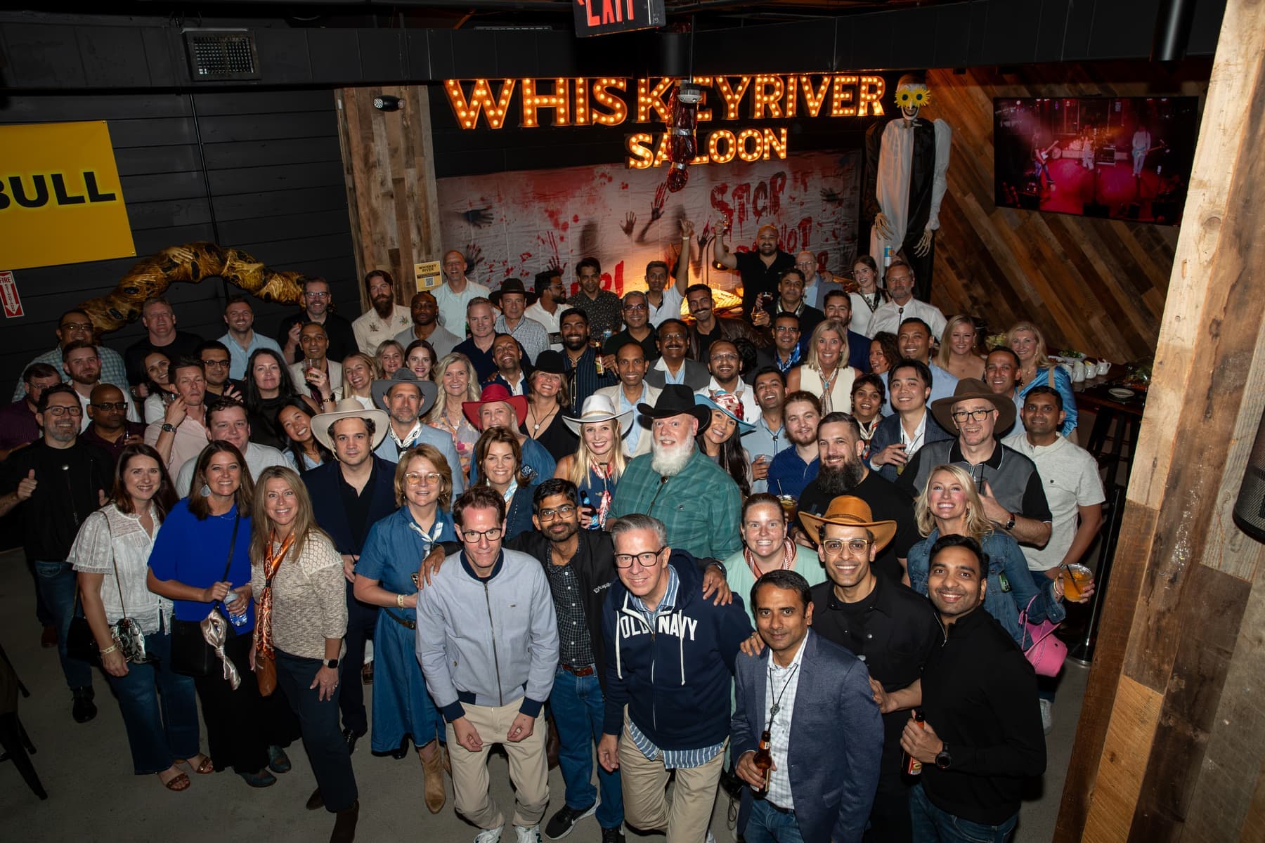 A large group of Captivate guests posing under the Whiskey River Saloon sign